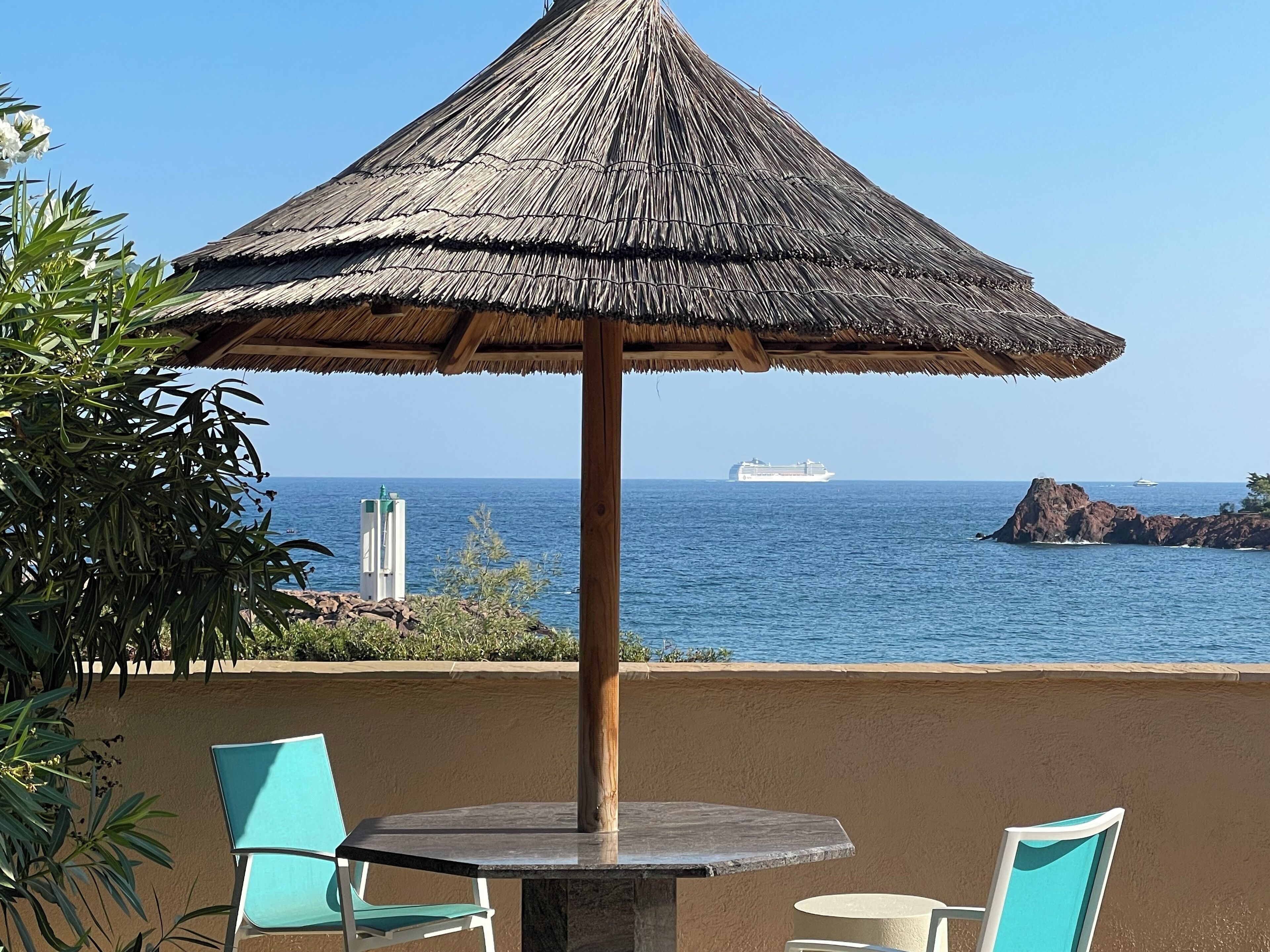 A beach umbrella with a thatched roof, a table, and two chairs.