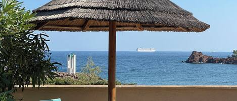 A beach umbrella with a thatched roof, a table, and two chairs.