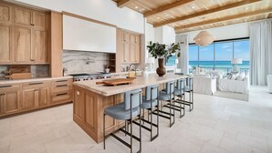 Una cocina moderna con armarios de madera, salpicadero de mármol y una isla grande con taburetes de bar.