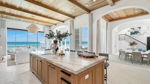 Una cocina espaciosa con una isla grande, armarios de madera y vistas al océano.