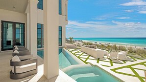 Un hotel moderno con piscina, mobiliario exterior y vista a la playa.