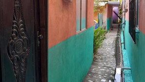 A narrow corridor with a tiled floor, a sign indicating 'Suite 3 Familiar Com Cozinha', and an air conditioning unit on the wall. - Hospedagem Chapéu Virado  (Belém)