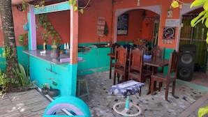 A small outdoor seating area with a counter, wooden chairs, a table, and a speaker. - Hospedagem Chapéu Virado  (Belém)