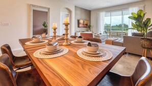 A dining area with a wooden table set for four, surrounded by leather chairs. - Champions Gate condos by UNE (Davenport)