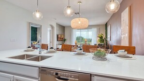 A modern kitchen with a central island, pendant lights, and a dishwasher. - Champions Gate condos by UNE (Davenport)