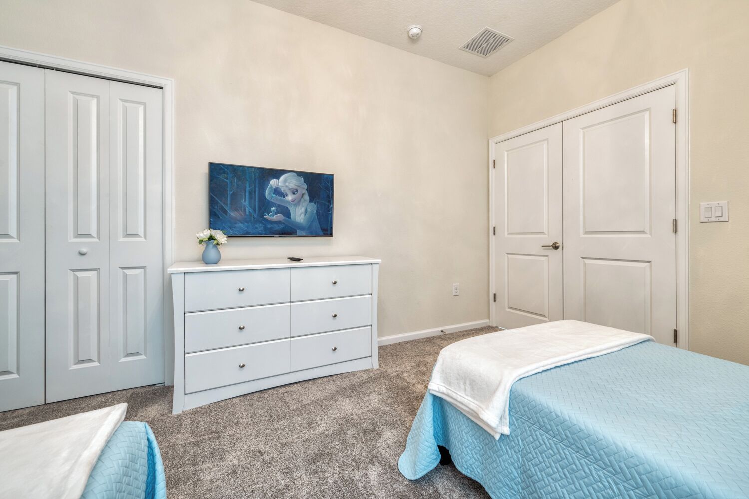 A bedroom with two beds, a dresser, and a painting on the wall.