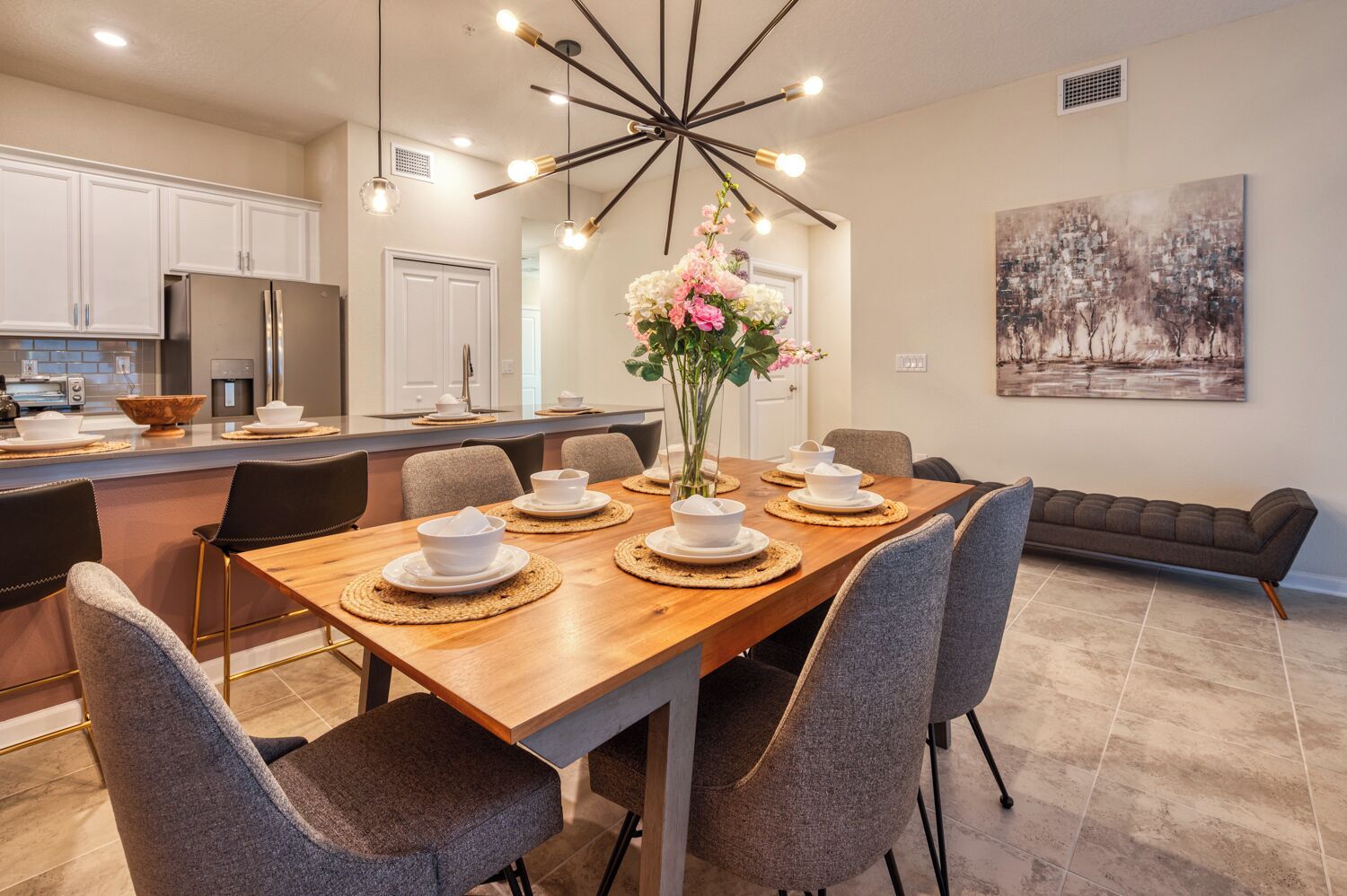 A modern kitchen with white cabinets, a stainless steel refrigerator, and a dining area with a wooden table set for four.