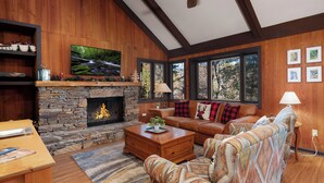 Una sala de estar acogedora con chimenea de piedra, sofá de cuero y televisión montada en la pared.