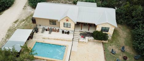 A two-story house with a swimming pool, outdoor seating, and a star emblem on the front.