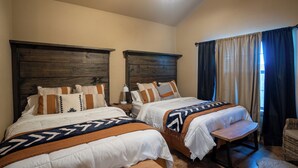 A bedroom with two beds, wooden headboards, and a nightstand with a lamp.