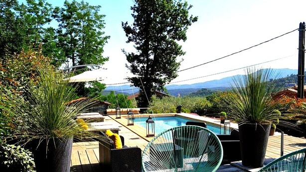 A poolside area with a wooden deck, lounge chairs, and potted plants. - Magnificent Cottage in Payzac With Pool ! (Payzac)