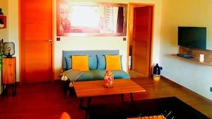 A living room with a sofa, a table, and a television. - Magnificent Cottage in Payzac With Pool ! (Payzac)