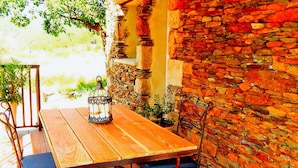 A wooden table with chairs, a lantern, and a stone wall. - Magnificent Cottage in Payzac With Pool ! (Payzac)