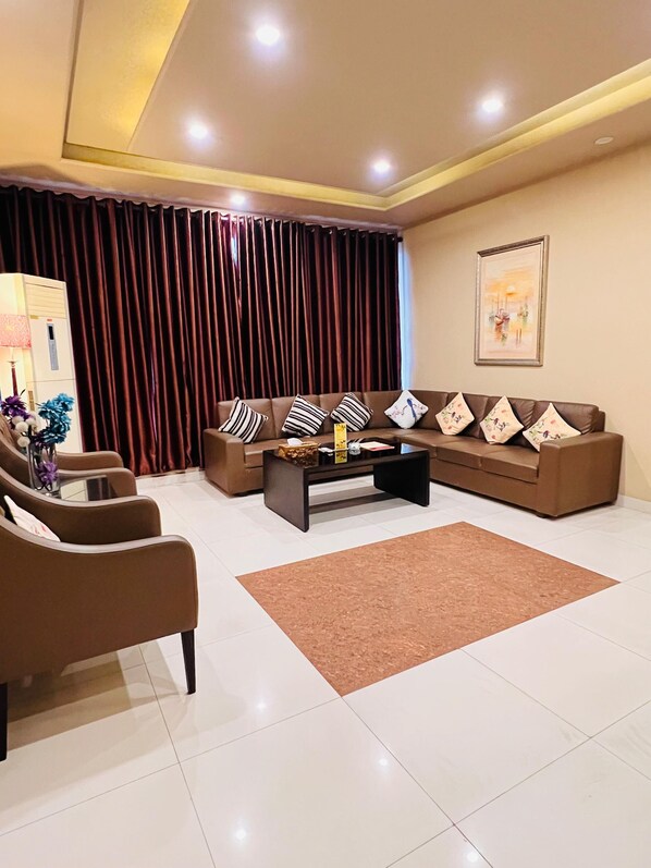 A modern living room with a sofa set, a coffee table, and a decorative vase. - Grand Regent Hotel and Suites (Faisalabad)