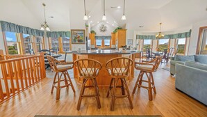 A spacious kitchen with a central island, wooden chairs, and a view of the outdoors.
