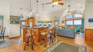A spacious kitchen with a central island, wooden bar stools, and a large window overlooking a scenic view.
