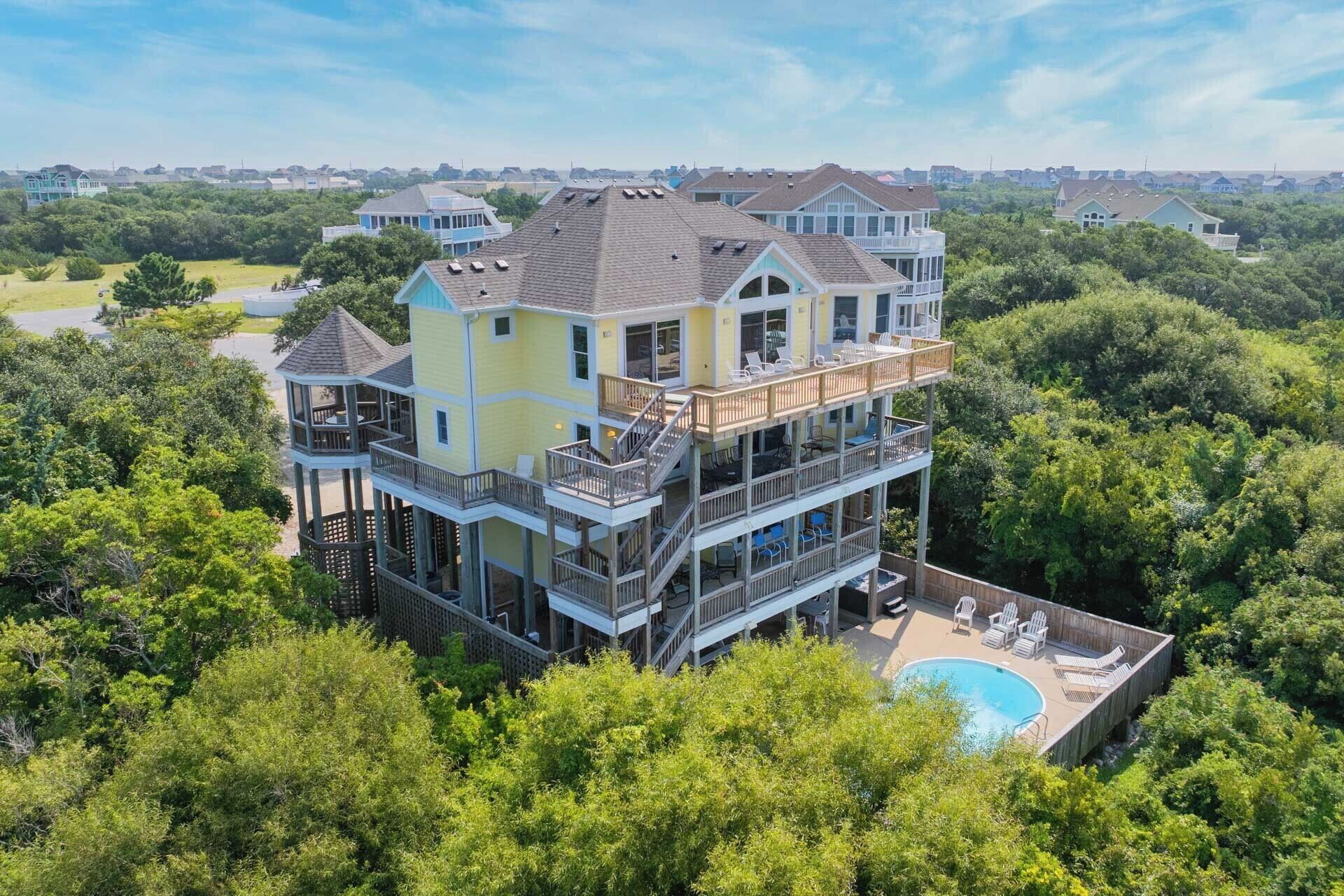 A multi-story house with a large deck, a swimming pool, and a view of the surrounding area.