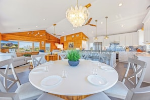 A modern kitchen with white cabinets, a blue backsplash, and a dining area with a round table and gray chairs.