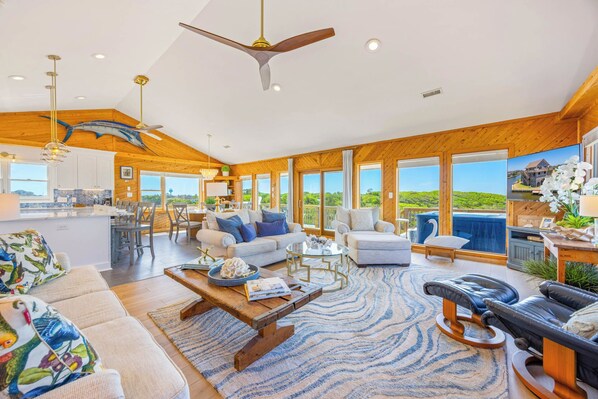 A spacious living area with a large window, a ceiling fan, and a dining area.