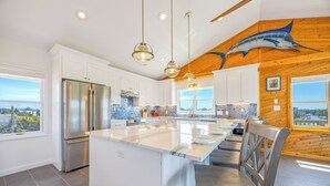 A modern kitchen with a central island, stainless steel appliances, and a view of the city. - Canalfront Dog Friendly Home w/ Hot Tub, Private Boat Ramp/Dock, Cargo Lift (Avon)