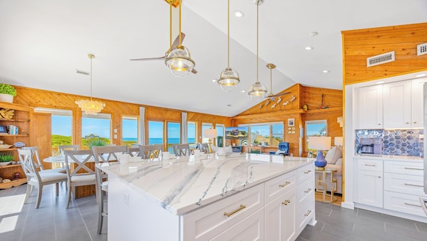 A spacious kitchen with a large island, wooden paneling, and a view of the ocean. - Canalfront Dog Friendly Home w/ Hot Tub, Private Boat Ramp/Dock, Cargo Lift (Avon)