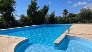 Una piscina azul cristalina con un borde de baldosas y una escalera metálica.