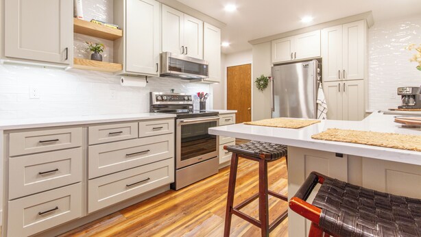 A modern kitchen with white cabinetry, a stainless steel refrigerator, an oven, and a microwave. There is a wooden countertop and a bar stool. - Midtown Comfort & Convenient home -  3 bedrooms in Dubuque (Dubuque)