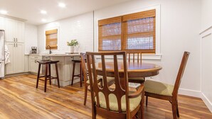A kitchen with wooden flooring, white cabinets, a dining table with chairs, and a window with blinds. - Midtown Comfort & Convenient home -  3 bedrooms in Dubuque (Dubuque)