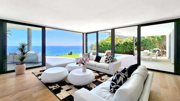 Un salon moderne doté d’une grande baie vitrée donnant sur la mer.