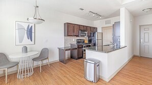 A modern kitchen with a central island, dark wooden cabinets, stainless steel appliances, and a white countertop. - Landing | Stylish 1BD, Rooftop Lounge, Gym (Fort Worth)