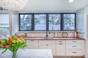 A kitchen with a large window, a sink, and a marble countertop. - 1913 Restored Lux Retreat|Walk2Dwtn/Ferry/5 bathrm (Bradenton)