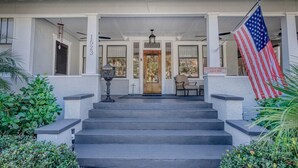 A two-story building with a porch, steps leading to the entrance, and an American flag. - 1913 Restored Lux Retreat|Walk2Dwtn/Ferry/5 bathrm (Bradenton)