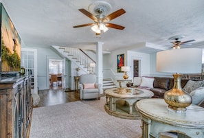 A spacious living room with a staircase, a round coffee table, and a large vase. - DOWNTOWN BRADENTON RETREAT | SWIM SPA • AMI • IMG (Bradenton)