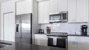 A modern kitchen with stainless steel appliances, white cabinetry, and a black countertop. - Landing | Spectacular 2BD, Gym, Clubhouse (Tampa)