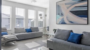 A modern living room with two grey sofas, a bench, and a floor lamp. - Landing | Spectacular 2BD, Gym, Clubhouse (Tampa)