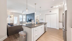 A modern kitchen with a central island, white cabinetry, and stainless steel appliances. - Landing | Stylish 3BD, Clubhouse, Gym (Tampa)