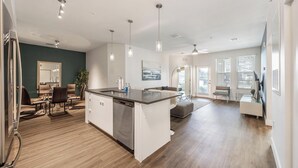 A modern kitchen with a central island, a dining area with a table and chairs, and a living space with a sofa and a coffee table. - Landing | Stylish 3BD, Clubhouse, Gym (Tampa)