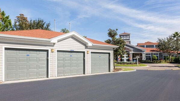 Il s’agit d’un bâtiment à deux étages, doté d’un toit recouvert de tuiles rouges et d’une façade blanche. On y trouve un grand garage avec deux portes grises, ainsi qu’une petite fontaine dans le jardin.
