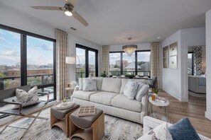 Una sala de estar moderna con un sofá grande, un comedor y vistas a la ciudad.