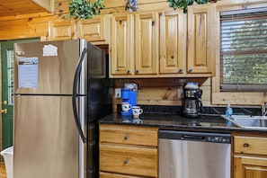 A kitchen with wooden cabinets, a stainless steel refrigerator, a coffee maker, and a dishwasher. - Stunning Views, Games, and Relaxation! (GATLINBURG)