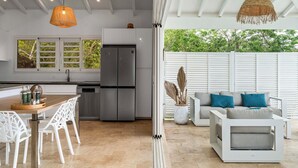 Una cocina moderna con refrigerador empotrado, muebles blancos y una zona de comedor con sillas blancas.