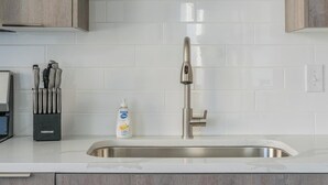 A modern kitchen with a stainless steel sink, a faucet, and a soap dispenser. - Landing | Amazing 2BD in Fountain Heights (Birmingham)