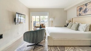 A hotel room with a bed, a desk, a chair, a TV, and a window with a view of the outside. - Landing | Chic Studio, Gym, Pool (Raleigh)