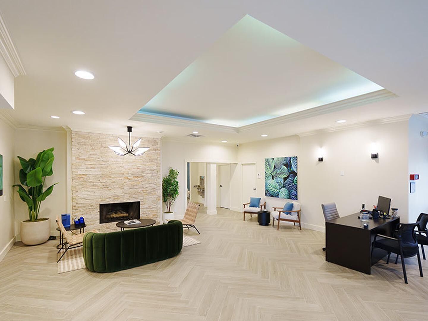 A spacious lobby with a stone wall, a fireplace, a reception desk, and seating areas.