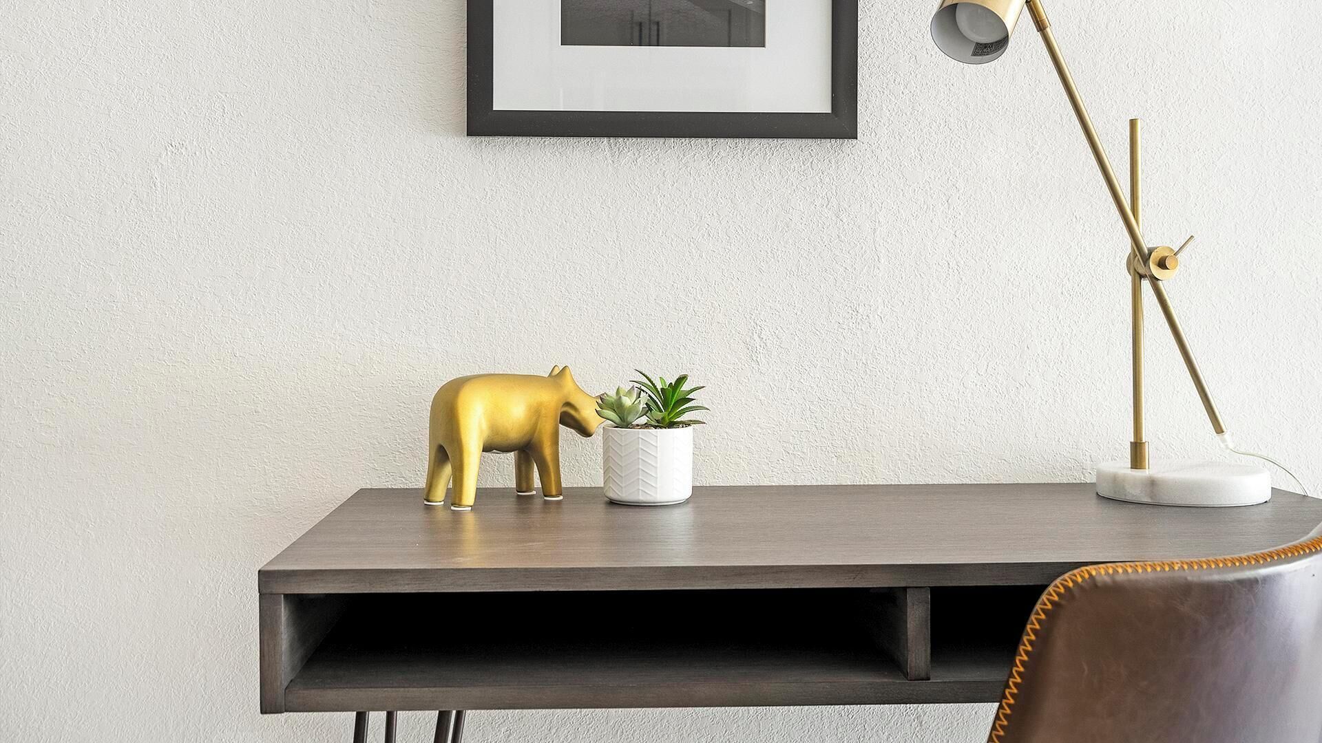 Ett skrivbord med en gyllene elefantfigur och en krukväxt.