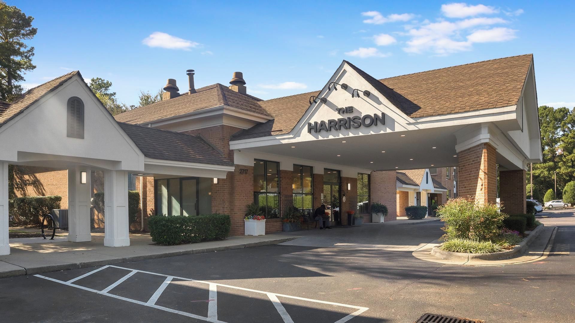 A hotel with a covered entrance, a brick facade, and a parking lot.
