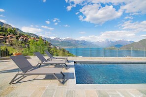 A poolside area with lounge chairs, a clear view of a lake, and mountains in the background. - VILLA DEI VENTI-TIVAN by Curti rentals (Calozzo)