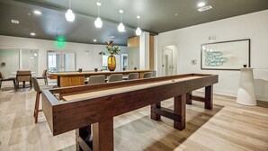 A billiards table in a modern room with wooden flooring, recessed lighting, and a minimalist decor.