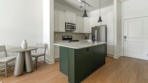 A modern kitchen with white cabinets, a central island, and stainless steel appliances.