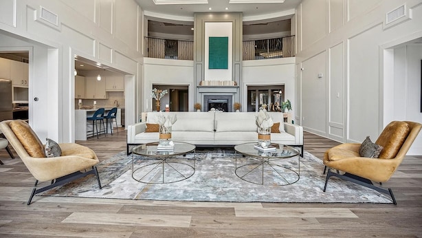 A spacious living area with a central white sofa, two armchairs, and a fireplace.